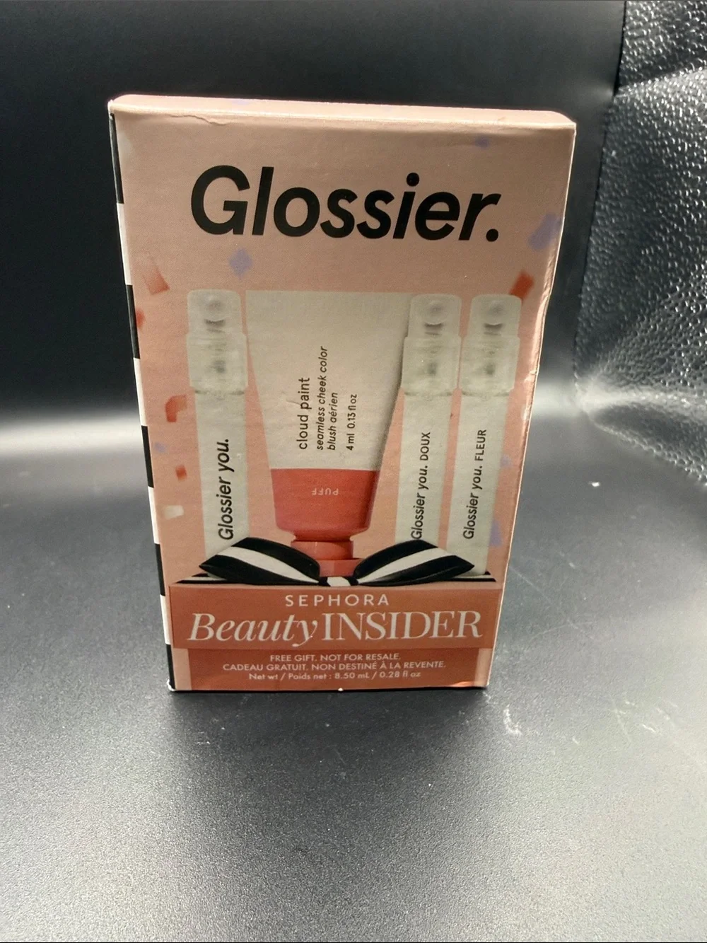 Glossier mini Cloud Paint blush in Puff alongside three mini fragrance samples